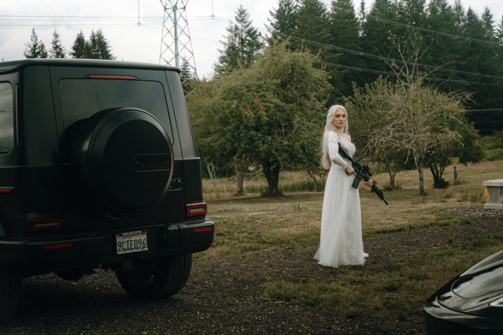 bride holding a rifle, posing with their guns and cars