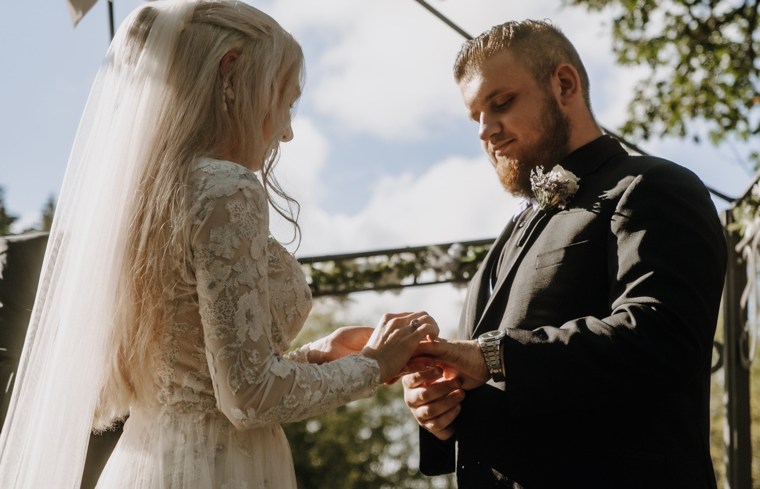 Cinematic and moody wedding photography of a couple at Villa Ragalie in Oregon, capturing romantic and timeless moments. Groom placing ring on brides finger during ceremony.