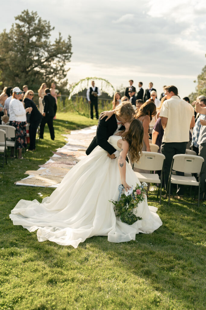 couple walking down aisle to confetti bend oregon wedding photography kiss dip 